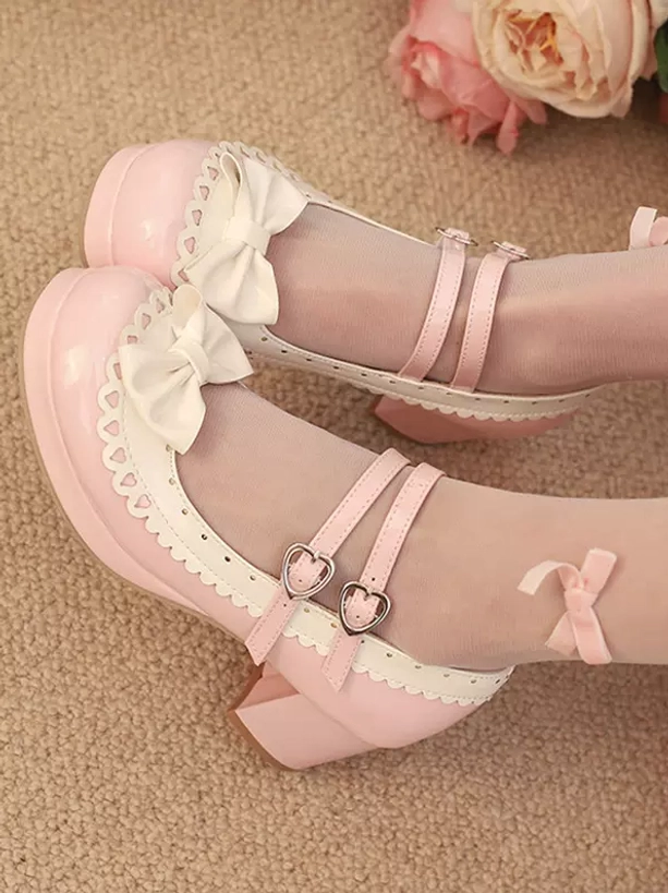 Light pink sweet lolita mary jane shoes with rose bow embellishments and color block design displayed in flat lay overhead view on carpet with artificial roses, featuring decorative heart-shaped buckles and scalloped white trim details