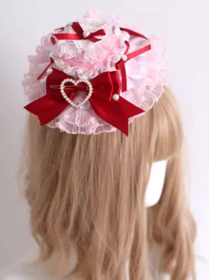 Lolita mini hat headdress rear three-quarter view showing layered pink lace ruffle trim and red ribbon bow crown accents with pearl heart decoration