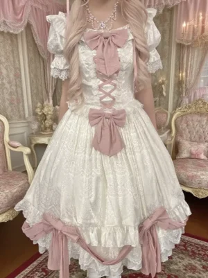 Sweet Lolita OP dress front view with vintage European indoor backdrop, model wearing white jacquard dress with dusty pink bows and lace-trimmed ruffled puff sleeves, complete sweet lolita styling