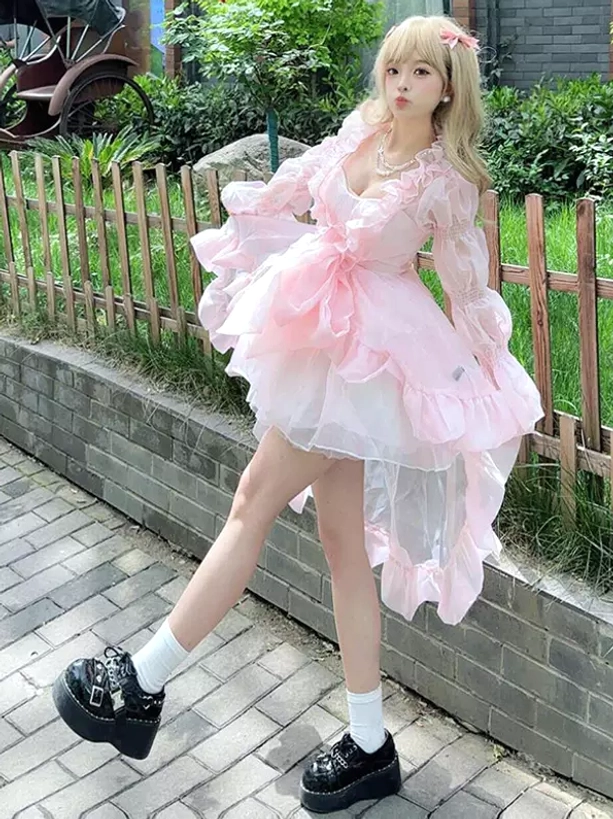 Sweet lolita OP dress full body side view showing high-low flounced skirt silhouette, platform loafer footwear, large satin waist bow focal point detail