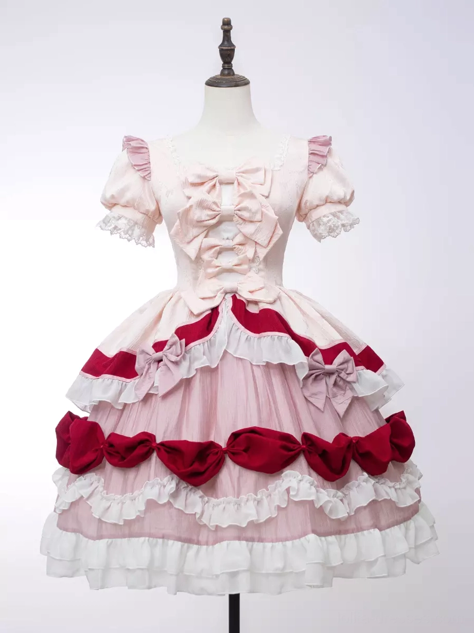 Sweet Lolita one-piece dress studio display on dress form with pure white background showing square neck with front bow, layered ruffled skirt, and cream-pink-red color matching