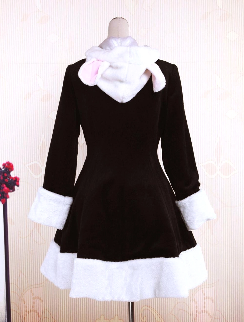 Rear mannequin display of black wool lolita overcoat featuring cute bunny ear hood with pink inner lining and back silhouette details