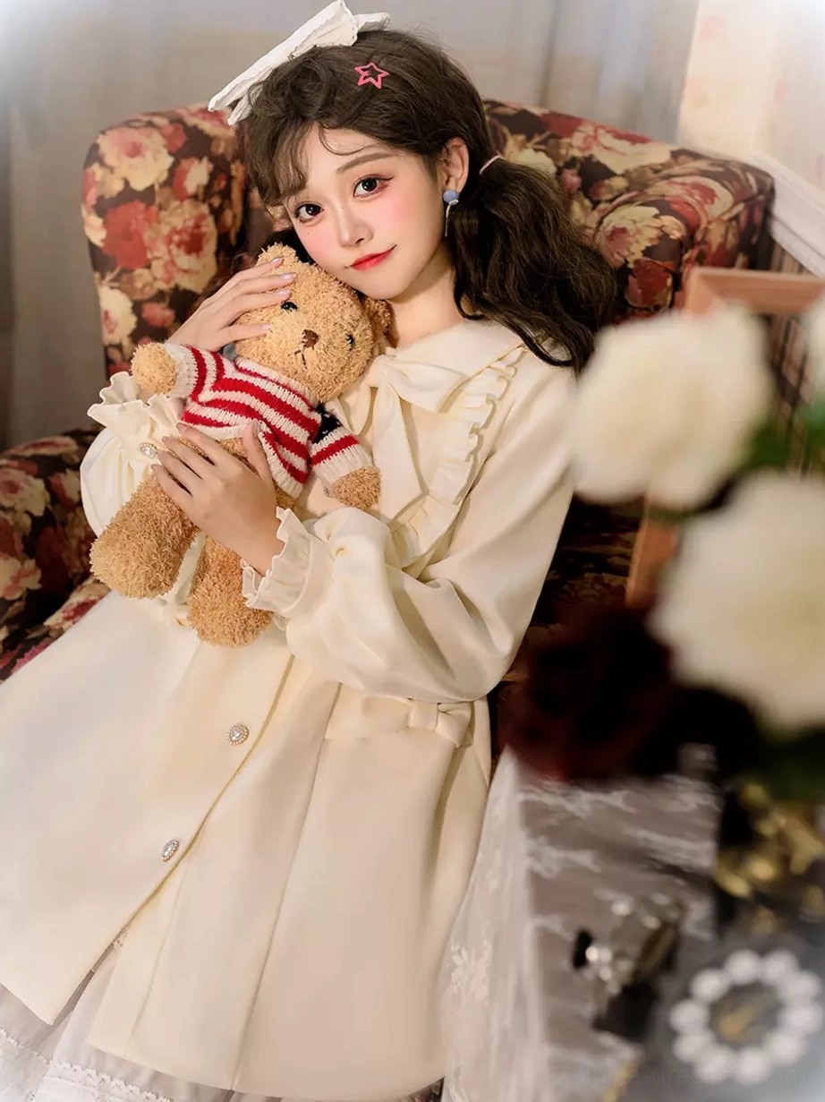 Lolita wool overcoat three-quarter side profile view showing waist strap and ruffled collar trim on model leaning on floral sofa