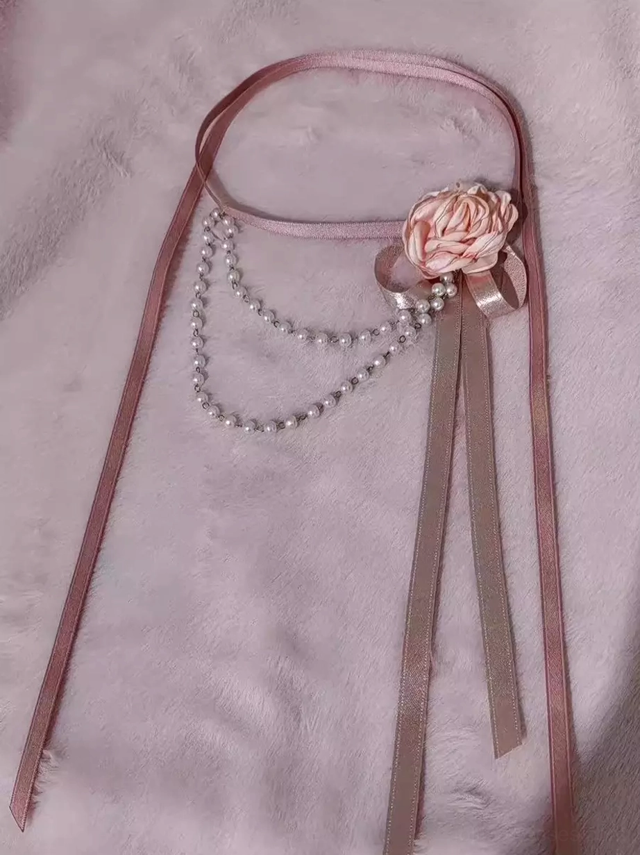Sweet Lolita pink satin choker with double pearl chain drape, 3D hand-crafted rose with bow, and long ribbon tails on pink plush background