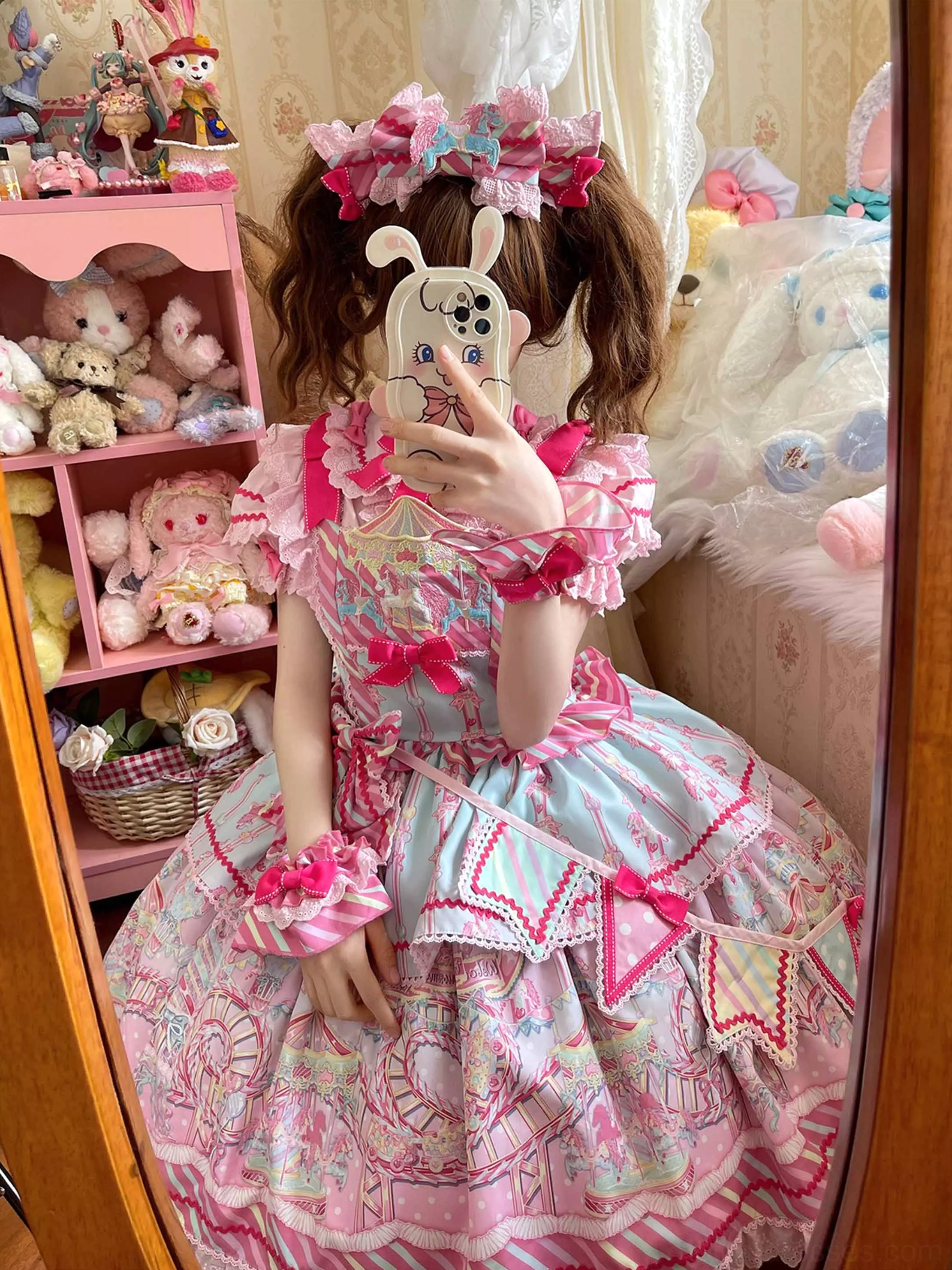 Girl wearing pink sweet lolita dress with matching hair bow and wrist bow, mirror selfie with plush toy studio background
