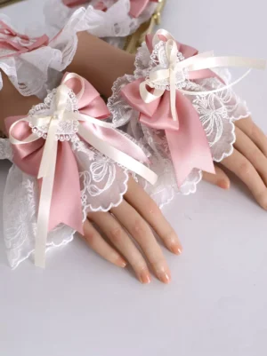 Sweet Lolita pink lace wrist cuffs with soft pink satin bows, white embroidered lace details, and ivory ribbon accents displayed on artificial hands from left oblique angle