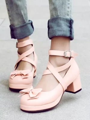 Sweet Lolita pastel pink platform shoes with bow decoration and cross ankle straps worn by model with denim, front-on display showcasing chunky heel and round toe