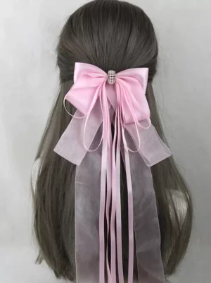 Baby pink satin bow hair clip with rhinestone center embellishment and mixed satin organza ribbon streamers displayed on mannequin with long hair, sweet lolita headwear accessory back view