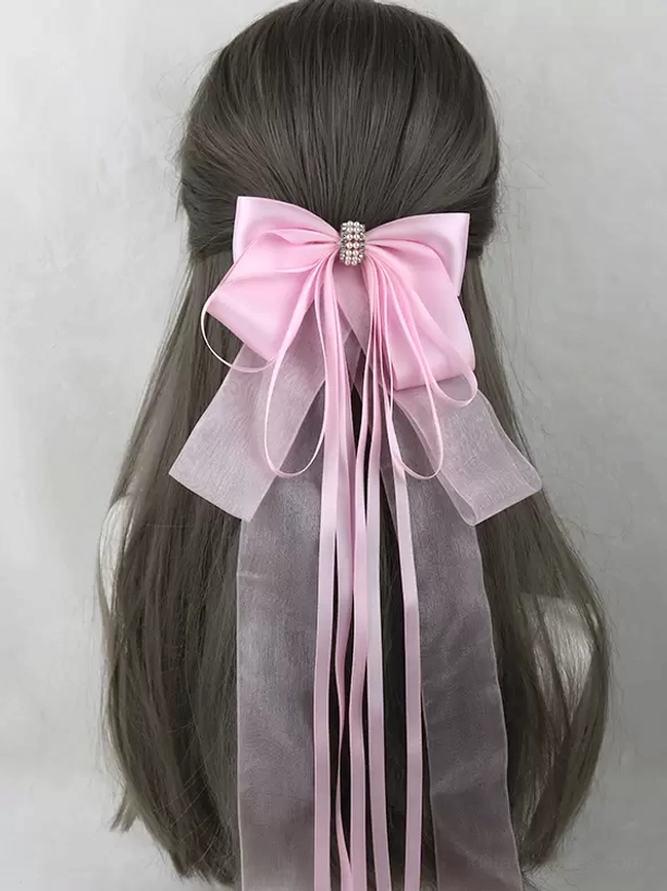 Baby pink satin bow hair clip with rhinestone center embellishment and mixed satin organza ribbon streamers displayed on mannequin with long hair, sweet lolita headwear accessory back view