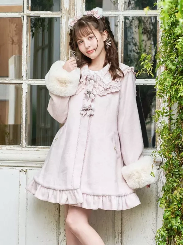 Pink sweet lolita winter wool coat with sailor lace collar and faux fur cuffs worn by model in front of retro window with green plants three-quarter view