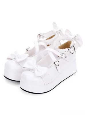 Sweet Lolita platform Mary Jane shoes in white with heart-shaped buckle straps, decorative bows, and cross ankle straps - three-quarter front view showing paired shoes on white background