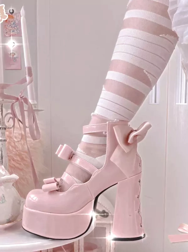 Sweet lolita platform pumps detailed close-up of bow embellishment, buckle straps, and chunky heel construction on pink satin background