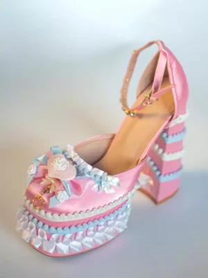 Sweet Lolita chunky heel platform pumps front three-quarter view with pink satin finish, ruffled platform sole, ornamental bow and flower decoration, rhinestone-adorned ankle strap
