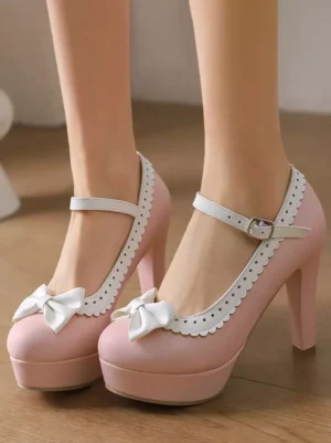 Front close-up view of Sweet Lolita platform high heel pumps in pink with white bow decoration and scalloped white trim detail on ankle buckle strap
