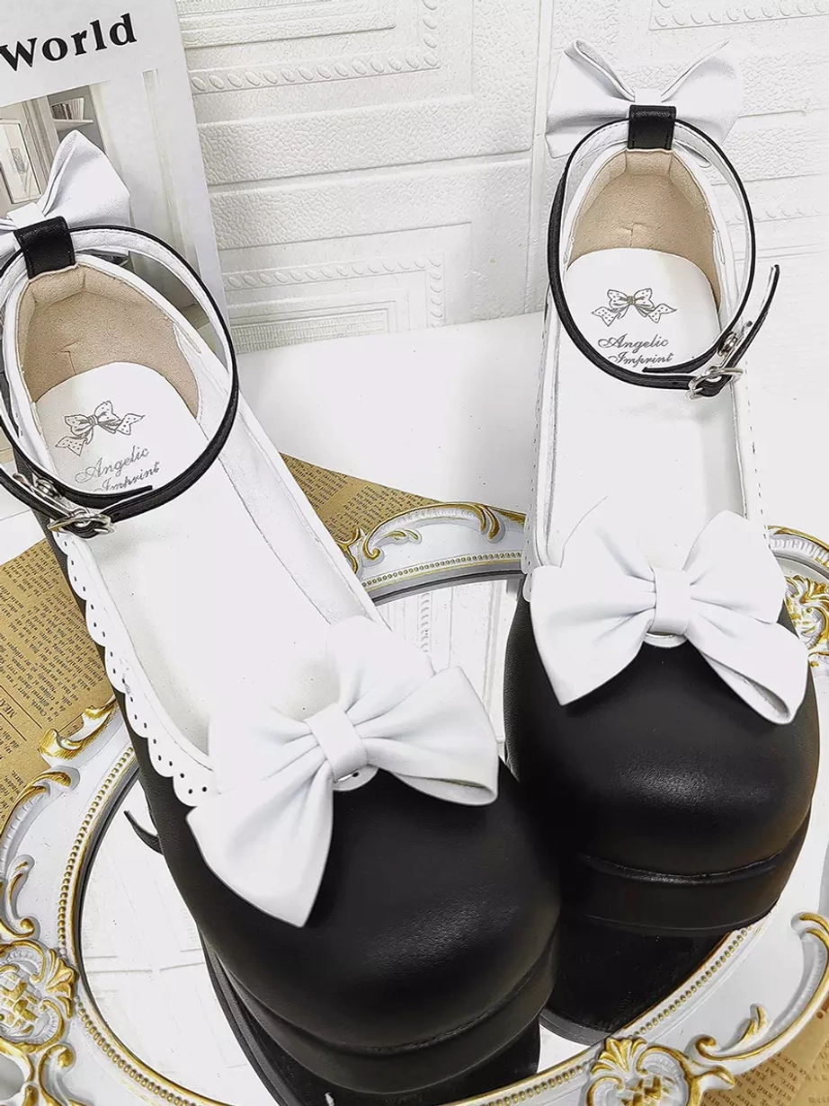 Overhead top-down view of Sweet Lolita pumps with black toe caps and white uppers, large white decorative bows, ankle buckle straps, and branded inner soles on ornate decorative tray