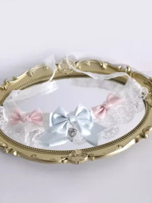 Sweet Lolita rococo lace choker top-down perspective displayed on vintage gold oval mirror, showcasing layered light blue and pink bows, white lace trim details, and hanging rhinestone pendant charm