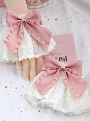 Sweet Lolita oversleeves with pink satin bow and ruffled off-white lace, displayed flat lay style with mannequin hand and whimsical props