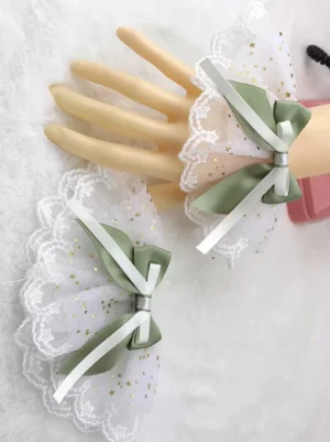 Sage green satin bow with white star-printed ruffled mesh wrist cuffs, delicate lace trim, Sweet Lolita accessory set on mannequin hands
