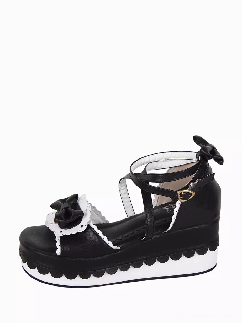 Sweet Lolita platform sandal rear side view displaying ankle strap with metal heart buckle, heel bow embellishment, scalloped platform sole edge on white background