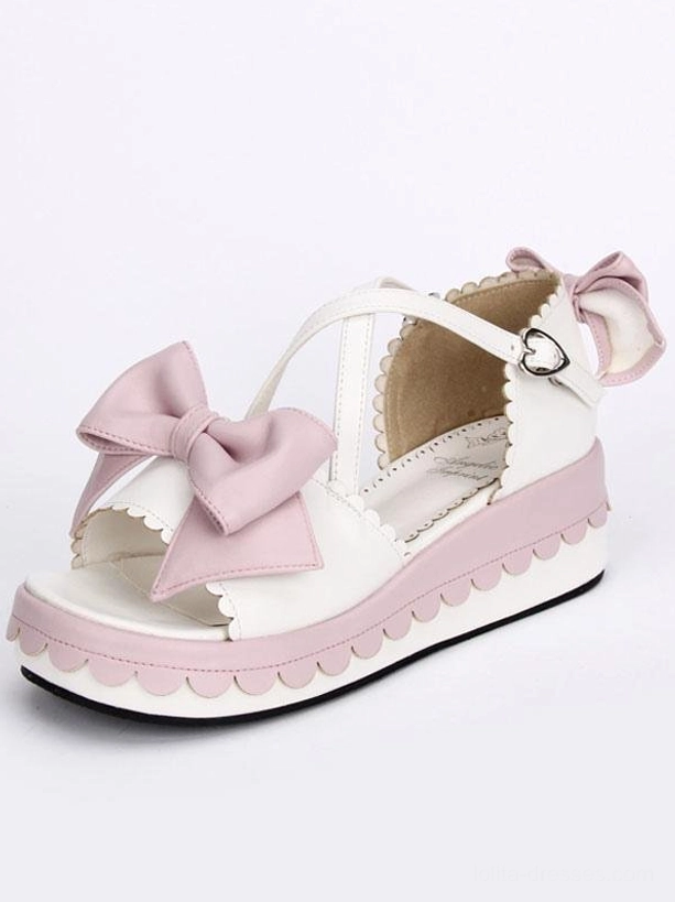 Single lolita platform sandal front close-up side view with clear detail of pink bow decoration, heart buckle fastening and scalloped platform edge