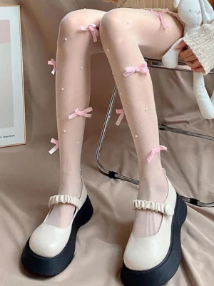 Sweet lolita decorative sheer tights side leg view showing pink ribbon bows and scattered faux pearls on nude stockings with bunny plush accessory