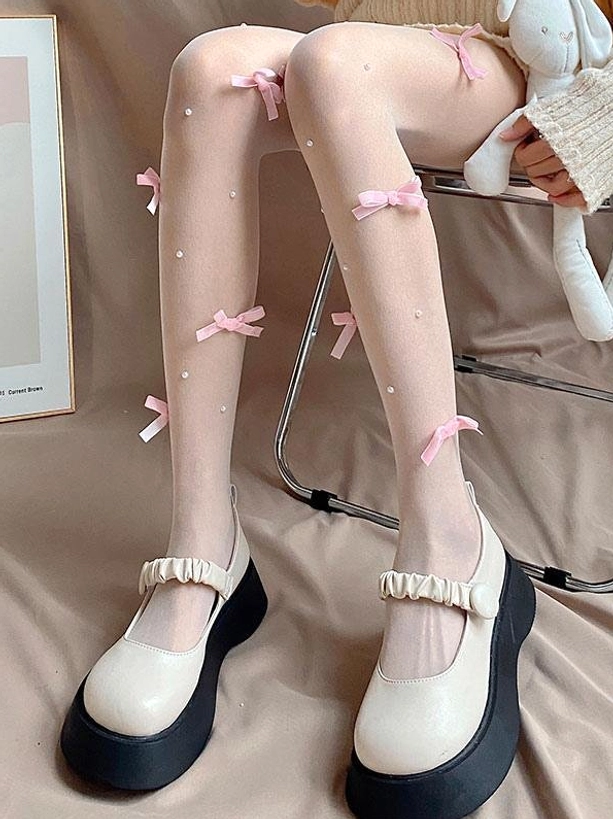 Sweet lolita decorative sheer tights side leg view showing pink ribbon bows and scattered faux pearls on nude stockings with bunny plush accessory