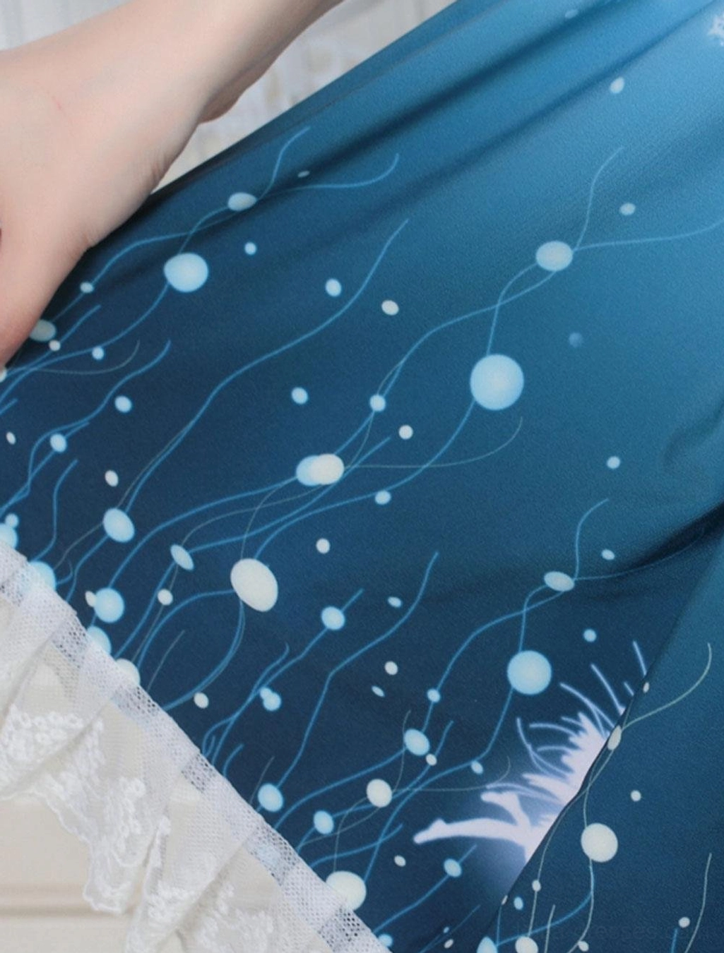 Side detail view of sweet lolita SK skirt showing dark blue base fabric with bubble and vine motifs and lace edge border