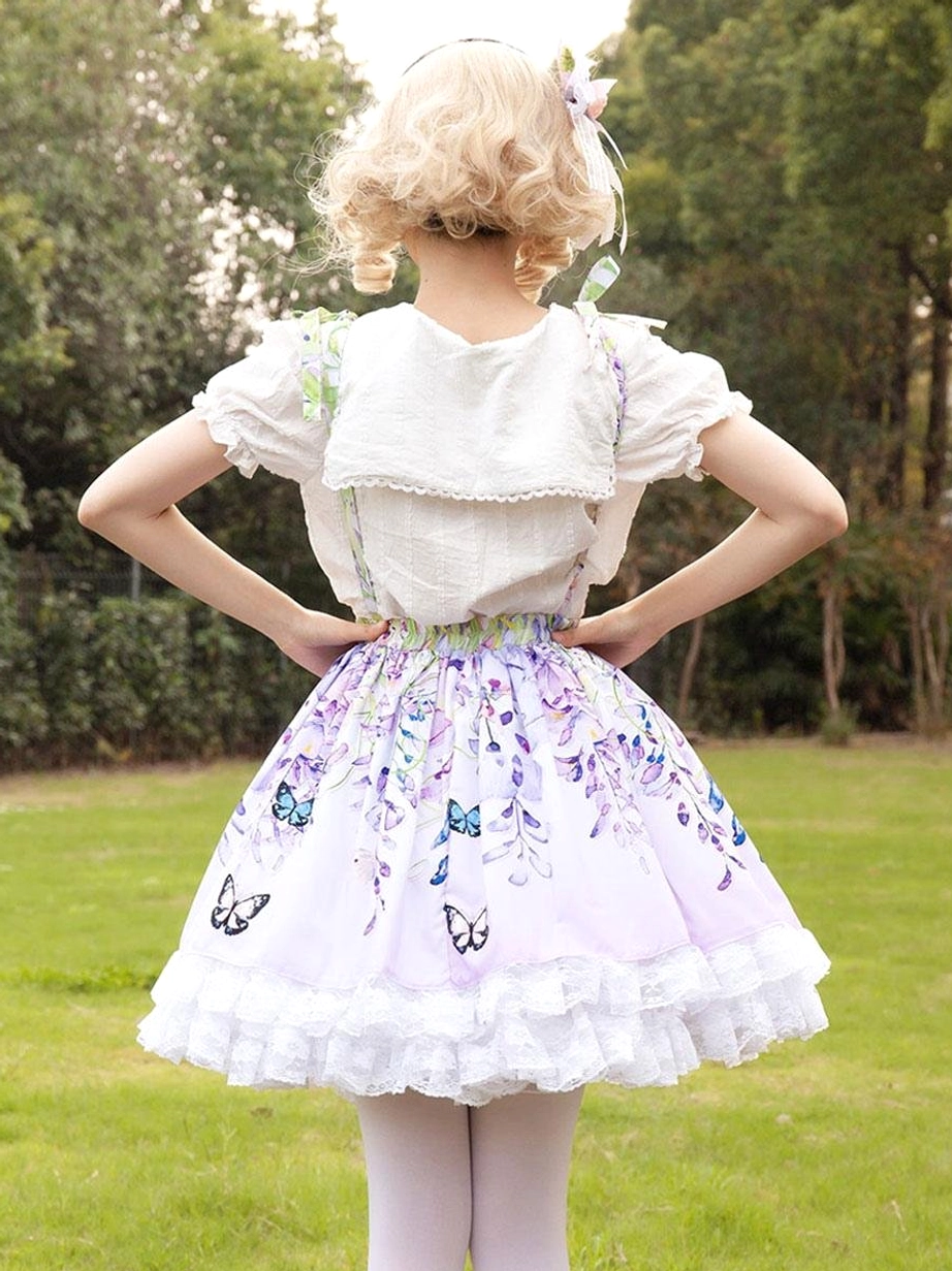 Back view of lilac floral lolita suspender skirt with white ruffled hem and white doll collar blouse back panel outdoor lawn background