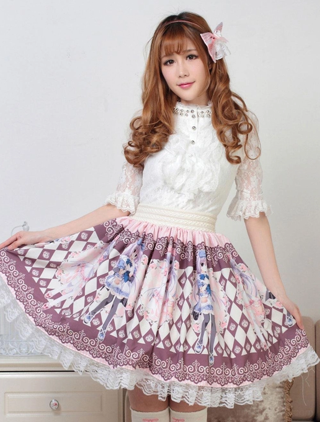 Pink sweet lolita skirt with argyle diamond print and ruffled lace trim, front low angle view with white blouse and pink hair bow, indoor studio setting