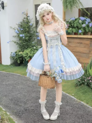 Sweet lolita light sky blue jsk dress three-quarter view showing square neckline, ruffled shoulder straps, tiered layered ruffles hem, and lace-up front detail with matching blonde model styling