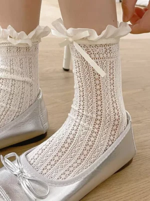 Close-up detailed view of ecru white lolita socks showing intricate hollow knit mesh pattern and ruffled cuff with silver ballet flats