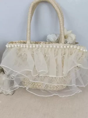 Sweet lolita straw handbag side three-quarter view displaying textured woven straw construction pearl bag opening trim and decorative flower arrangement
