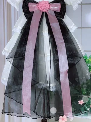 Sweet Lolita detachable bow train tail accessory with black and pink organza bow, pink rose embellishment, front view with floral background