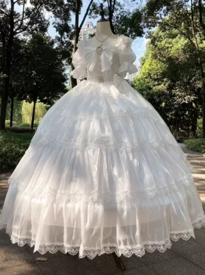 Sweet Lolita wedding dress slightly angled front view showcasing diamond chest bow detail, tulle skirt volume, and outdoor park setting with natural lighting