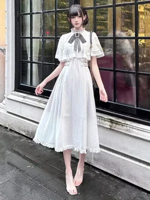 Sweet lolita white dress with decorative waist buckles ruffled sleeve cuffs and lace skirt hem full front standing pose outdoor wet pavement