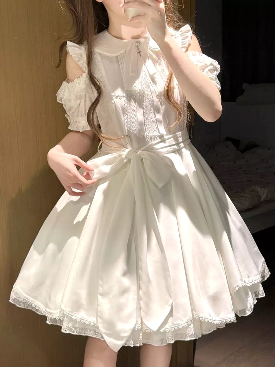 White sweet lolita mini dress front three-quarter view on model with peter pan collar cold-shoulder puff sleeves waist bow ruffled skirt hem indoor home setting