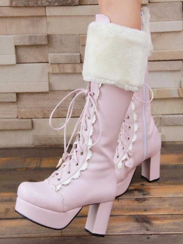 Sweet pink lolita platform boots on model's legs side-front angle with white fluffy cuff, lace trim, lace-up design, platform heel against wooden floor and stone wall background