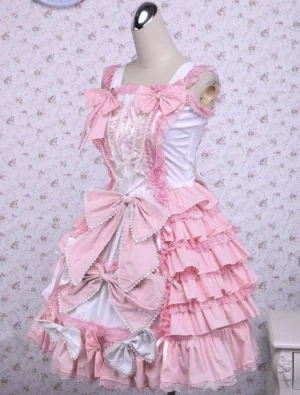 Pink sweet Lolita jumper dress three-quarter front view showing lace trims, front bow accents, and multi-layered ruffled skirt construction with pink and white color coordination