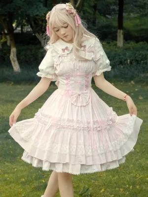 Sweet pink cotton Lolita jumper skirt with lace trim and corset bodice worn by model outdoors, showing front three-quarter view with layered ruffled skirt