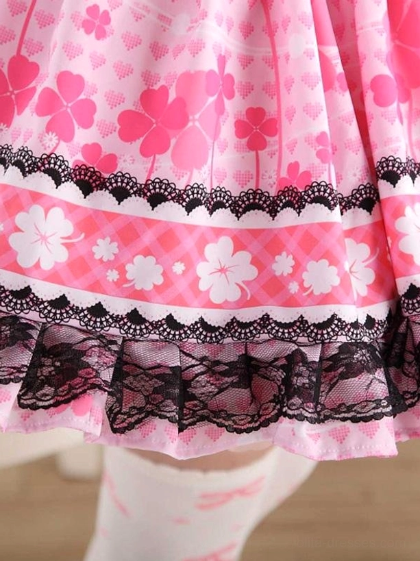 Close-up of sweet lolita skirt hem featuring black lace ruffle edging, pink plaid ribbon band accent, white floral print details on lace border