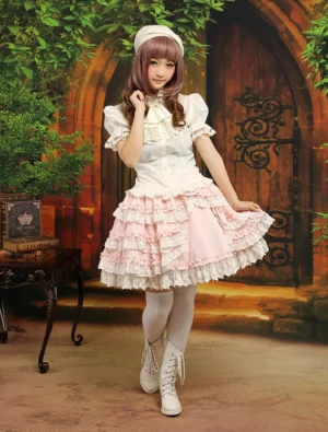 Pink and white Sweet Lolita skirt suit three-quarter perspective showing layered lace ruffles and decorative bow detail with model hand pose