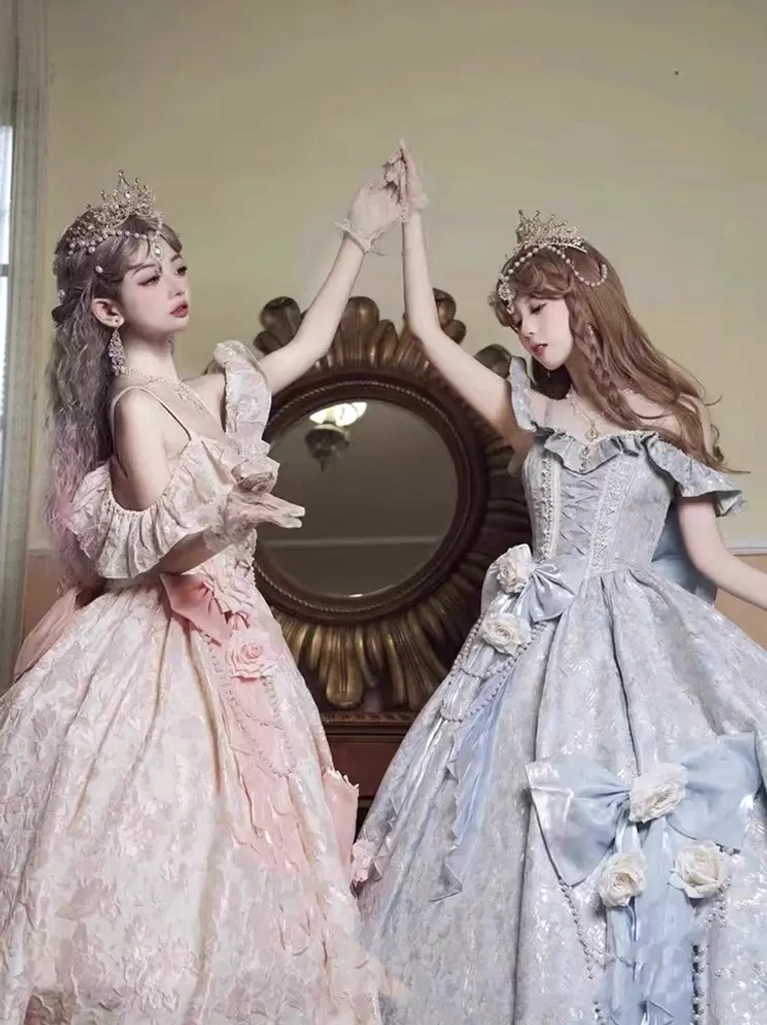 Two models dancing in pink and purple Classic Lolita gowns indoors showing off-shoulder ruffles flower-bow adornments and elegant movement