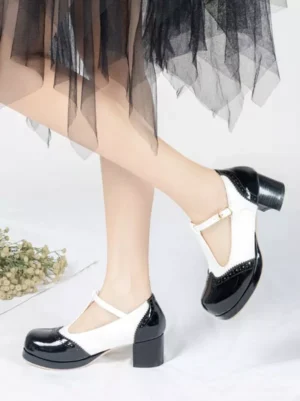 Black and white two-tone T-strap Mary Jane platform pumps with round toe and chunky block heel, rear side leg view on model wearing black tulle skirt, sweet lolita footwear