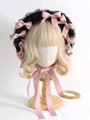 Front view of Victorian Lolita tea party bonnet with ruffled black mesh brim and pink satin bows on blonde mannequin wig