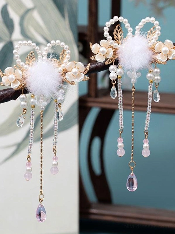 East Asian inspired decorative hair clips featuring gold metal, soft white pom-poms, dangling pearl-adorned tassels with pink purple pendants, wooden furniture display
