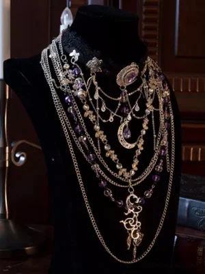 Ornate Gothic lace choker with purple gemstone accents and vintage metal filigree crescent moon pendant detail, displayed on black velvet mannequin
