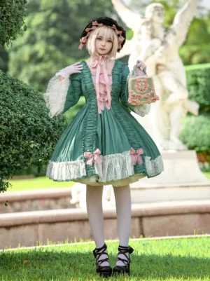 Vintage green Rococo lolita op dress front angle with model holding floral handbag, pink bow details on skirt hem, garden statue background setting