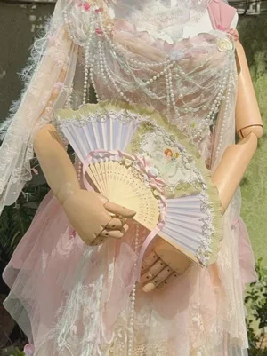 Vintage folding hand fan displayed on wooden mannequin wearing coordinating pink lolita dress with pearl chain accessories, showcasing how the fan complements classical lolita outfits and tea party styling