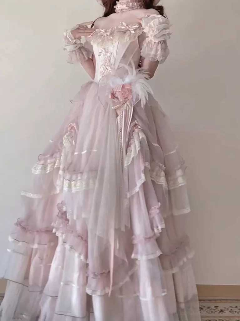Pink vintage formal lolita dress three-quarter view displaying off-shoulder corset top feather and flower waist decoration multi-tiered ruffled tulle skirt elegant historical silhouette