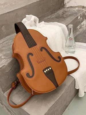 Violin-shaped coffee brown PU leather Lolita crossbody bag displayed on concrete steps with accessories showing sculptural silhouette and dark brown faux violin decoration details